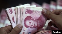 FILE - A bank clerk counts Chinese banknotes at a branch of Industrial and Commercial Bank of China in Huaibei, Anhui Province, June 8, 2012. The central banks of 14 African countries are considering adding the Chinese yuan to their foreign reserves.