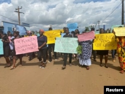 FILE - Schoolchildren, their parents and teachers hold a protest after gunmen opened fire at a school, killing at least six children as authorities claim, in Kumba, Cameroon, Oct. 25, 2020.