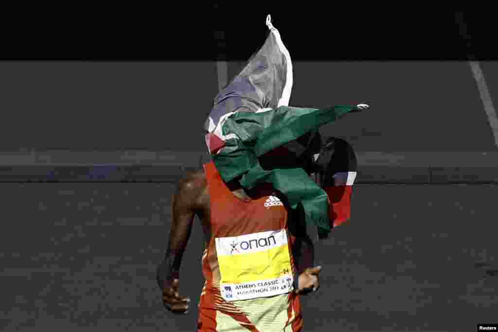 Kenya&#39;s Hillary Kipkogei Yego crosses the finish line to win the men&#39;s race of the 31st Athens Classic Marathon as a flag thrown by a fan covers his face at the Panathenaic stadium in Athens, Greece.