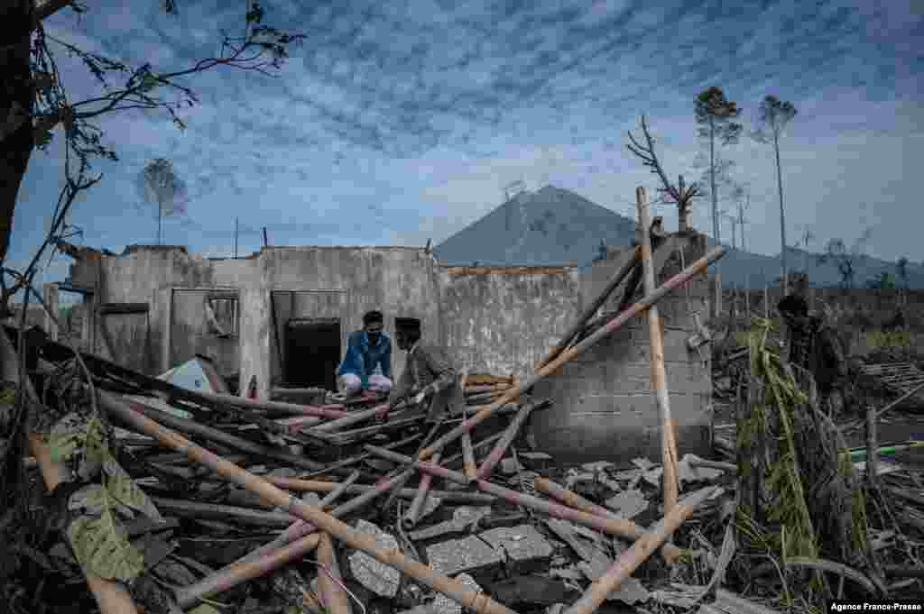 Villagers attempt to gather their belongings from their damaged home at Curah Kobokan village in Lumajang, Indonesia, after the Mount Semeru volcano burst and killed at least 34 people.