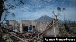 Penduduk desa menyelamatkan barang-barang mereka dari rumah mereka yang rusak di Desa Curah Kobokan di Lumajang pada 8 Desember 2021, setelah letusan Gunung Semeru. (Foto: AFP)