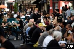 Customers eat sunday lunches at tables outside restaurants in Soho, in London. Sept. 20, 2020.