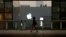 FILE - A woman walks past an Apple store in Beijing, China, July 28, 2016. 