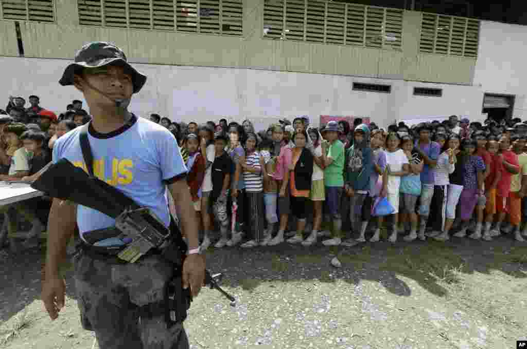 People line up for relief supplies at an evacuation center in New Bataan township, Compostela Valley, Philippines, December 6, 2012.