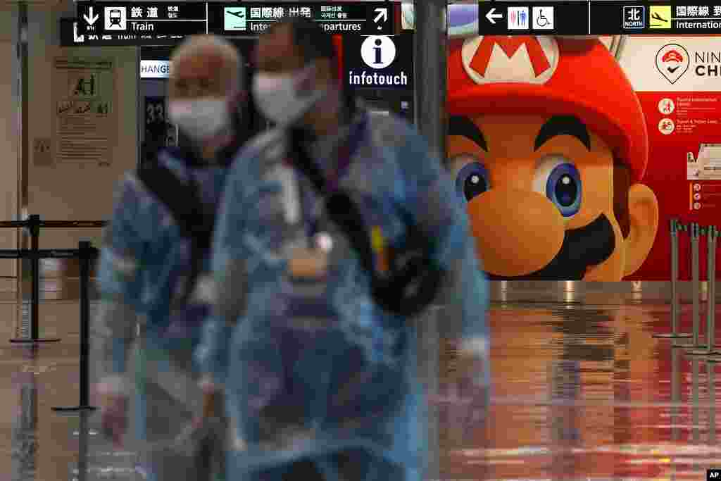 Medical personnel walk by as they wait for the arrival of international passengers at Narita International Airport, in Narita, east of Tokyo.