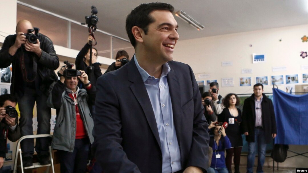 Pemimpin kubu oposisi dari partai Syriza, Alexis Tsipras, tersenyum sebelum memasukkan suaranya di sebuah TPS di Athena (25/1).