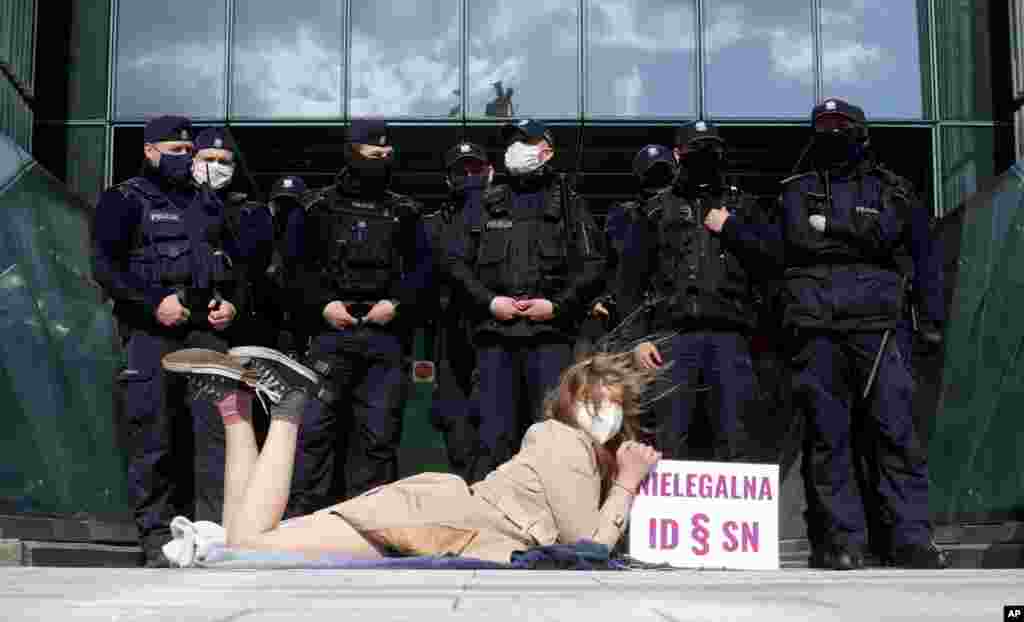 Policemen guard Poland&#39;s Supreme Court as a protester lies on the pavement in Warsaw.