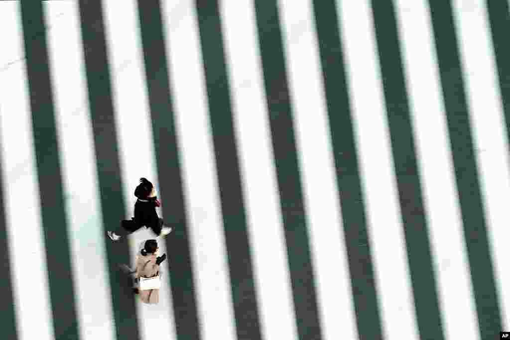 People wearing protective masks to help curb the spread of the coronavirus run along a pedestrian crossing in Tokyo. The Japanese capital confirmed more than 340 new coronavirus cases on Thursday. 