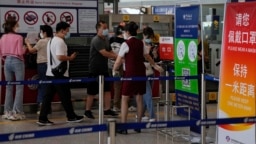 FILE - An airliner worker asks travelers to declare their health information after checking in at the international flight check in counter at the Beijing Capital International Airport in Beijing, Aug. 24, 2022.