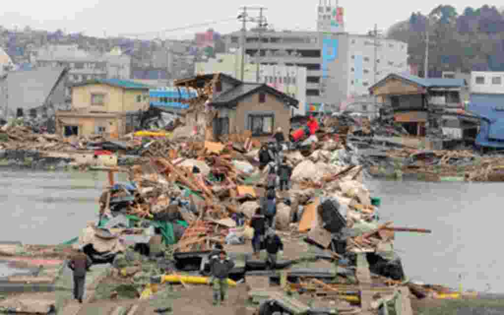 Los residentes atraviesan un puente cubierto de restos de elementos arrastrados por el agua en Ishinomaki, en la prefectura de Miyagi.