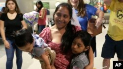 FILE - Buena Ventura Martin-Godinez, center, holds her son Pedro, left, as she is reunited with her daughter Janne, right, at Miami International Airport, July 1, 2018, in Miami, Florida.