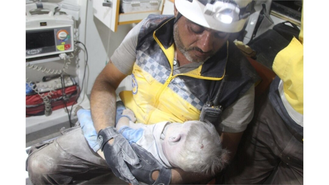 A Syria Civil Defence (White Helmets) member holds a child victim, pulled from the rubble after a deadly airstrike, said to be in Maarat al-Numan, Idlib province, Syria, Aug. 28, 2019.