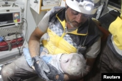 A Syria Civil Defence (White Helmets) member holds a child victim, pulled from the rubble after a deadly airstrike, said to be in Maarat al-Numan, Idlib province, Syria, Aug. 28, 2019.