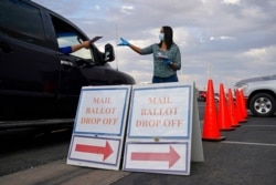 FILE - A county worker collects mail-in ballots in a drive-through ballot drop-off area at the Clark County Election Department in Las Vegas, Nov. 2, 2020.