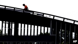 FILE - A worker is shown atop a building under construction in Hillsborough, N.C., July 1, 2019. The Labor Department reported July 5 that U.S. employers sharply stepped up hiring in June, adding a robust 224,000 jobs.