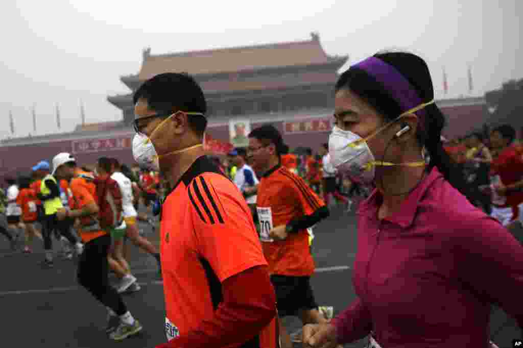 在雾霾中跑步的还有他们，2014年北京国际马拉松赛的参加者戴口罩在雾霾中跑步（2014年10月19日）