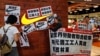 Protesters hold banners and placards during a protest outside a Nike shop at a shopping mall during Labor Day in Hong Kong, May 1, 2014 to support workers on strike at Yue Yuen Industrial Holdings Ltd. in China. 