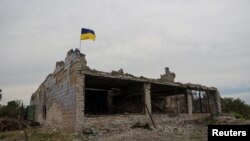 Ukrajinska nacionalna zastava na vrhu uništene zgrade vidi se u selu Neskučne