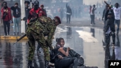 Kenya'da 20 Haziran 2024 tarihinde vergi artışlarına karşı düzenlenen bir gösteri sırasında bir protestocu polisin tazyikli su aracıyla vurulduktan sonra yerde ağlıyor ve başka bir protestocunun yanına tutunuyor