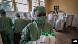 A worker carries bottles of liquid morphine after making it from powder, wearing protective clothing to protect from the effects of the drug and to prevent contamination, at the Pharmaceutical Laboratory of Rwanda in Butare, Rwanda, Nov. 7, 2019. 