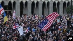 Manifestantes con banderas georgianas, ucranianas, estadounidenses y de la Unión Europea protestan ante el Parlamento de Georgia el 8 de marzo de 2023.