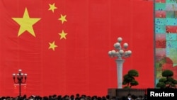 FILE - People walk in front of a giant Chinese flag at a central business district ahead of the 70th founding anniversary of People's Republic China in Chongqing, China, Sept. 13, 2019. (Chen Chao/CNS via Reuters)