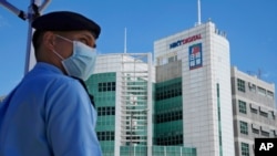  In this Thursday, June 17, 2021, file photo, a police officer stands guard outside the Apple Daily headquarters in Hong Kong after arresting the chief editor and four other senior executives of the newspaper under the national security law.