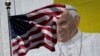 The U.S. flag flies in front of a mural of Pope Francis on the side of a building in midtown Manhattan in New York, Aug. 28, 2015.