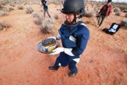 In this photo provided by the Japan Aerospace Exploration Agency (JAXA), a member of JAXA retrieves a capsule dropped by Hayabusa2 in Woomera, southern Australia, Dec. 6, 2020.