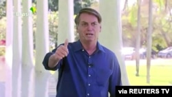 Brazil's President Jair Bolsonaro gestures as he speaks to the media on his positive coronavirus diagnosis in Brasilia, Brazil, July 7, 2020. 