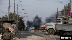 Seorang pemberontak pro-Rusia berpatroli di sebuah pos penjagaan saat asap hitam mengepul di dekat bandara Internasional Sergey Prokofiev, Donetsk, Ukraina Timur (23/9). 