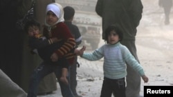 Children walk at a site hit by what activists said was a barrel bomb dropped by forces loyal to Syria's President Bashar al-Assad in Aleppo. (March 6, 2014.)