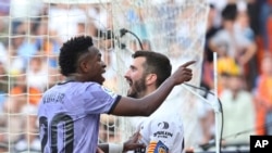 Real Madrid's Vinicius Junior, left, confronts Valencia fans in front of Valencia's Jose Luis Gaya during a Spanish La Liga soccer match between Valencia and Real Madrid, at the Mestalla stadium in Valencia, Spain, Sunday, May 21, 2023.