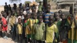 FILE - Children look at WFP food trucks arriving on February 13, 2016 in Pierri village of Jonglei State for the first time in three years since fighting broke out in December 2013 forcing locals here to survive on wild plants, trees and leaves.