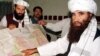 FILE - Jalaluddin Haqqani, right, the Taliban's Minister for Tribal Affairs, points to a map of Afghanistan during a visit to Islamabad, Pakistan, Oct. 19, 2001, as his son Naziruddin, left, looks on.