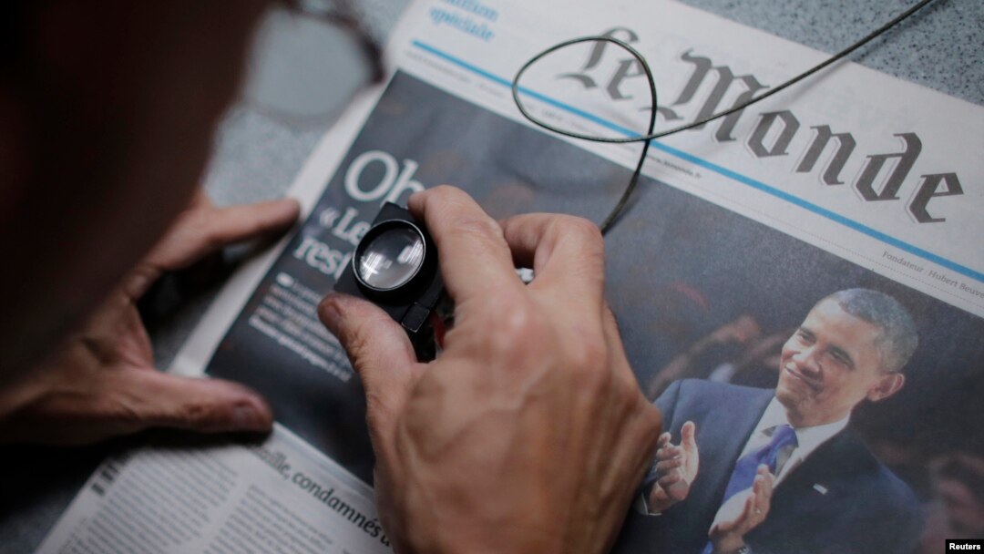 FILE - An employee checks a copy of the freshly-printed French daily evening newspaper Le Monde.