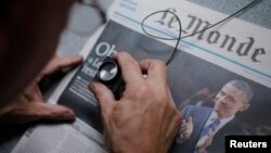 FILE - An employee checks a copy of the freshly-printed French daily evening newspaper Le Monde.