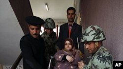 A woman on a wheelchair is helped down the stairs by army soldiers and policemen after casting her vote on the second day of parliamentary elections in Cairo November 29, 2011