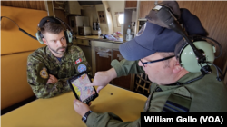 Major Doug Publicover, right, and Captain Maxime Cliche examine a tablet on board a Canadian CP-140 over the East China Sea, Oct. 14, 2024.