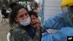 Sofia Pinto holds her son Antonio who cries out as he receives an influenza vaccine during a vaccination campaign in the Villa El Salvador neighborhood of Lima, Peru, June 26, 2020.