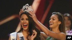 Catriona Gray dari Filipina, kiri, bereaksi saat ia menerima mahkota Miss Universe 2018 dari Miss Universe 2017, Demi-Leigh Nel-Peters dalam putara final kompetisi Miss Universe ke-67 di Bangkok, Thailand, Senin, 17 Desember 2018 (foto: AP Photo/Gemunu Amarasinghe)