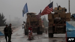 A line of US military vehicles drive through a checkpoint of the Internal Security Forces in Manbij as they head to their base on the outskirts of the northern Syrian city on December 30, 2018.