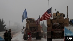A line of US military vehicles drive through a checkpoint of the Internal Security Forces in Manbij as they head to their base on the outskirts of the northern Syrian city on December 30, 2018.