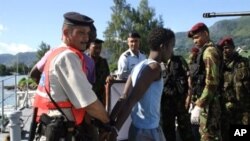 An arrested Somali pirate is handcuffed by police upon his arrival in Port Victoria, 31 Mar 2010, with the six Seychellois fishermen, who were taken hostage by Somali pirates