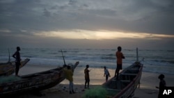 FILE —Senegalese youth gather around pirogues on the beach at dusk in Fass Boye, Senegal, Aug. 29, 2023. Officials in Senegal say at least two dozen people have died off Senegal’s northern coast and many were injured when a boat carrying migrants capsized on February 28, 2024.