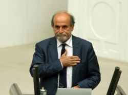FILE - Ertugrul Kurkcu, then a newly elected legislator from the pro-Kurdish People's Democracy Party, takes his oath during the Turkish parliament's first session in Ankara, June 23, 2015.