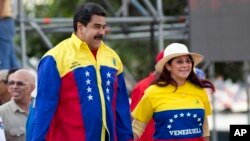 Venezuela's President Nicolas Maduro and first lady Cilia Flores jump during the closing campaign rally in Caracas, Venezuela, Dec. 3, 2015. 