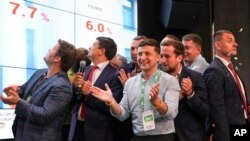 Ukrainian President Volodymyr Zelenskiy, center, applauds with his team as they look at election results at his party's headquarters after a parliamentary elections in Kyiv, Ukraine, July 21, 2019.