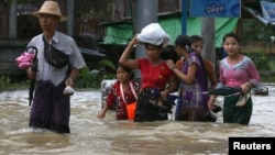 People wade through a flooded street in Bago, Myanmar, July 27, 2018. 