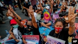 Pro-democracy activists flash a three-fingered symbol of resistance during a rally in Bangkok, Thailand, March 24, 2021, ahead of indictment against 13 protest leaders Thursday for allegations of sedition and defaming the monarchy.